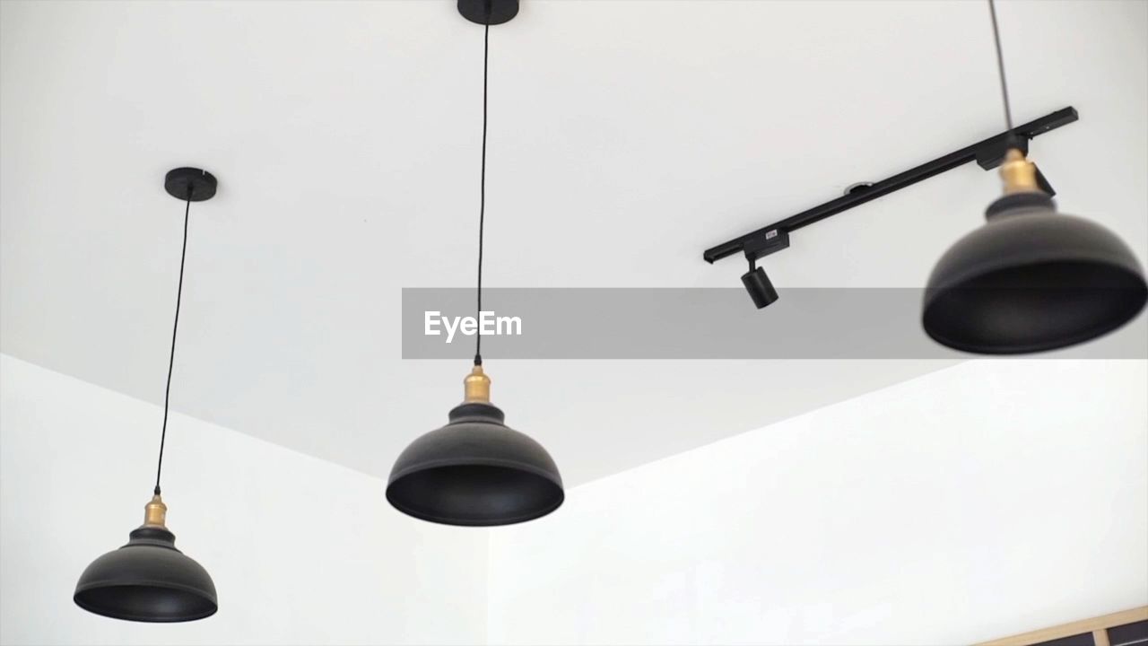 LOW ANGLE VIEW OF ILLUMINATED LIGHT BULB HANGING FROM CEILING