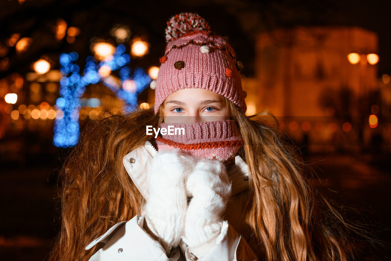Blonde teenager with long hair in winter clothes on festive winter evening