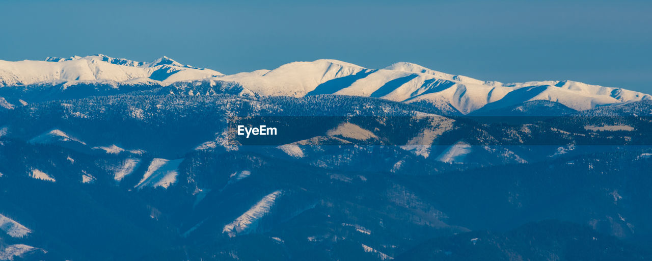 Scenic view of snowcapped mountains against clear blue sky