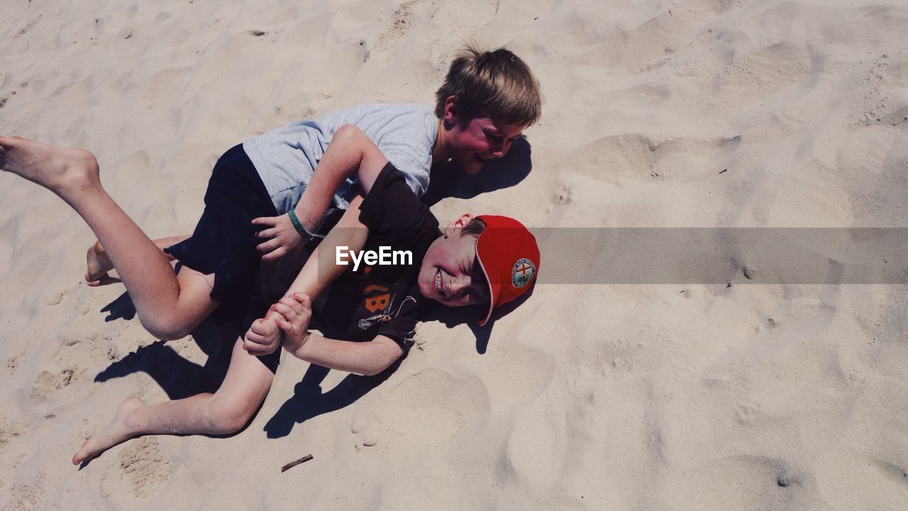 BOY PLAYING WITH ARMS RAISED ON SAND