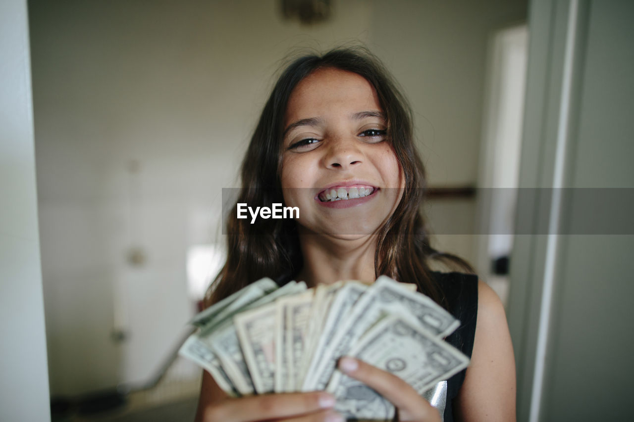 Portrait of cheerful girl with paper currency at home
