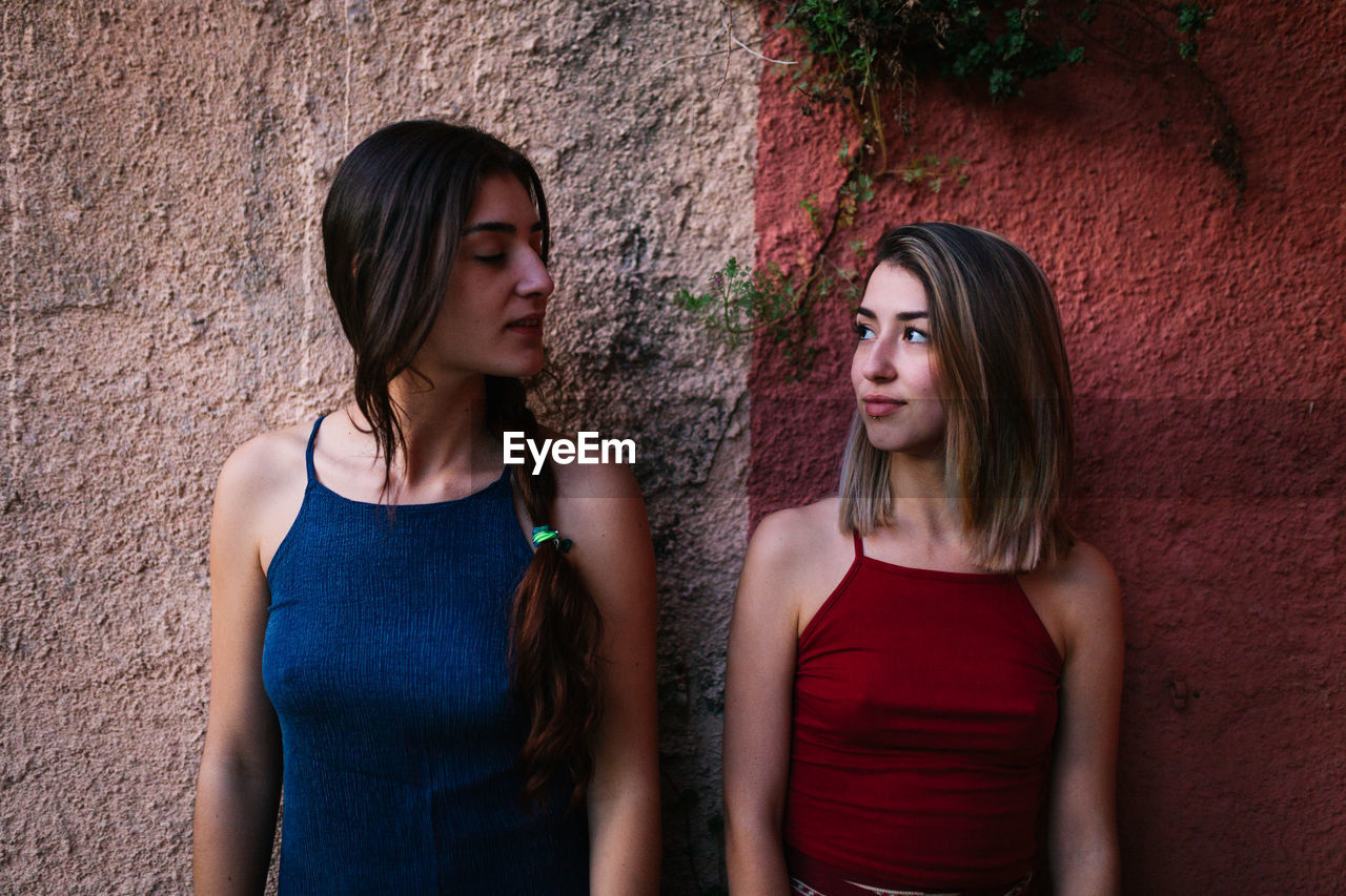 PORTRAIT OF A BEAUTIFUL YOUNG WOMAN AGAINST WALL OUTDOORS