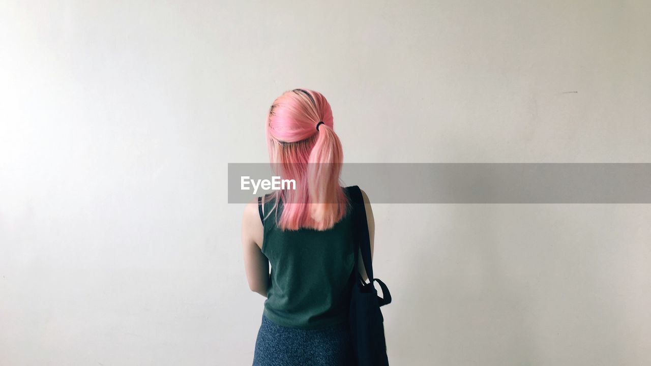 Rear view of woman with dyed hair standing against wall