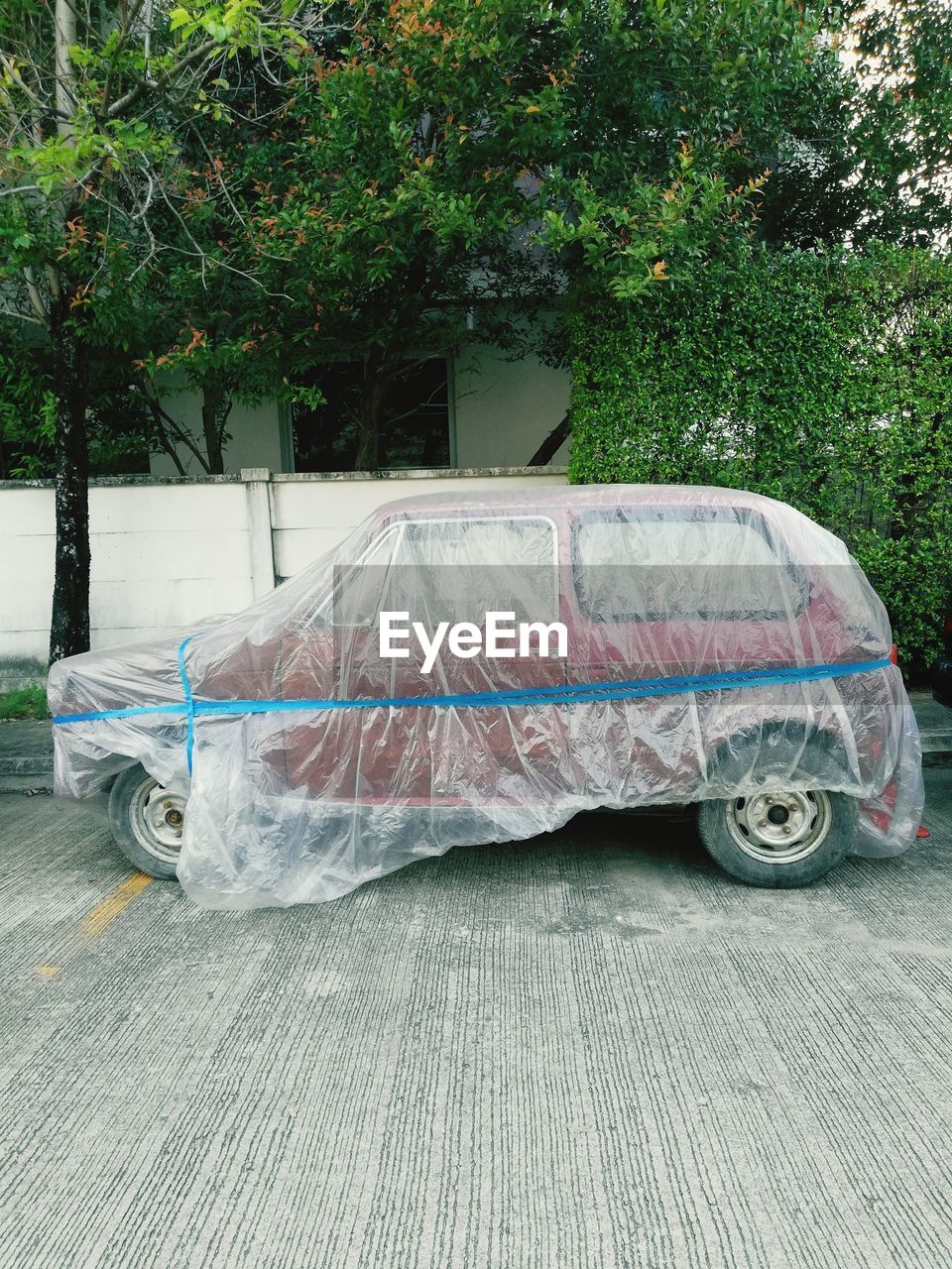 Covered car parked on street by trees