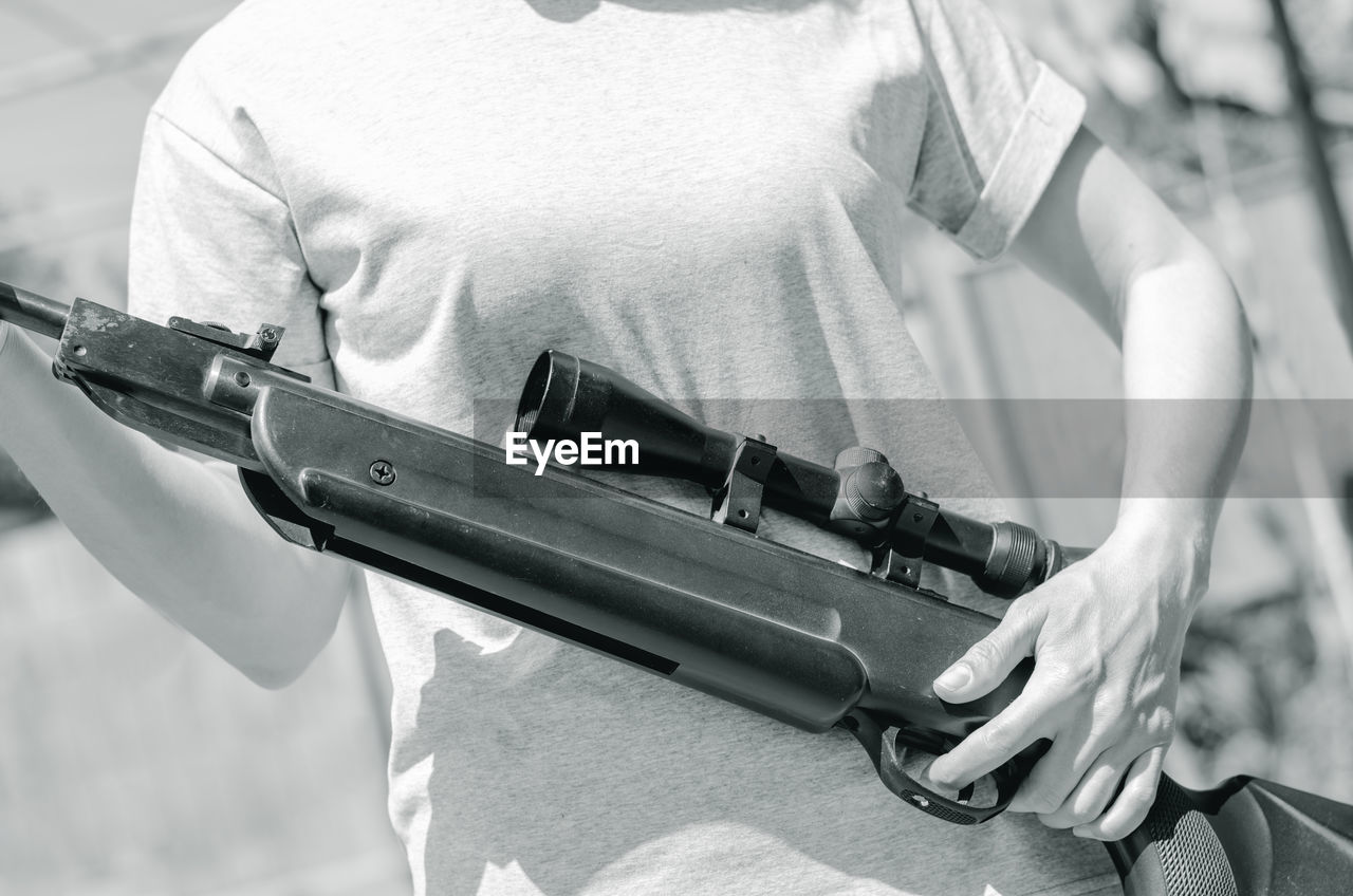 Sniper rifle in female hands. woman holding a rifle with an optical sight, close-up