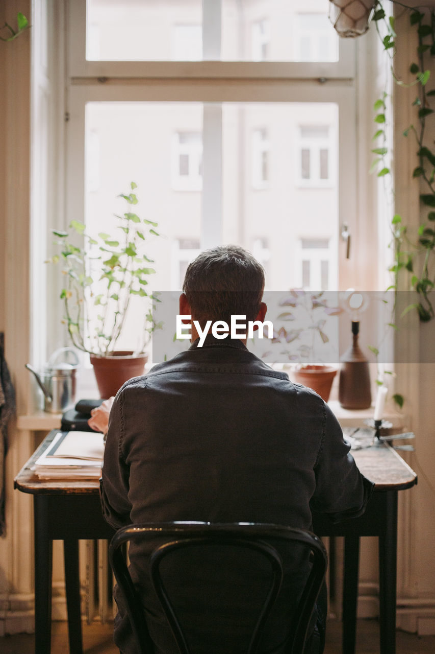 Rear view of businessman sitting on chair at home office