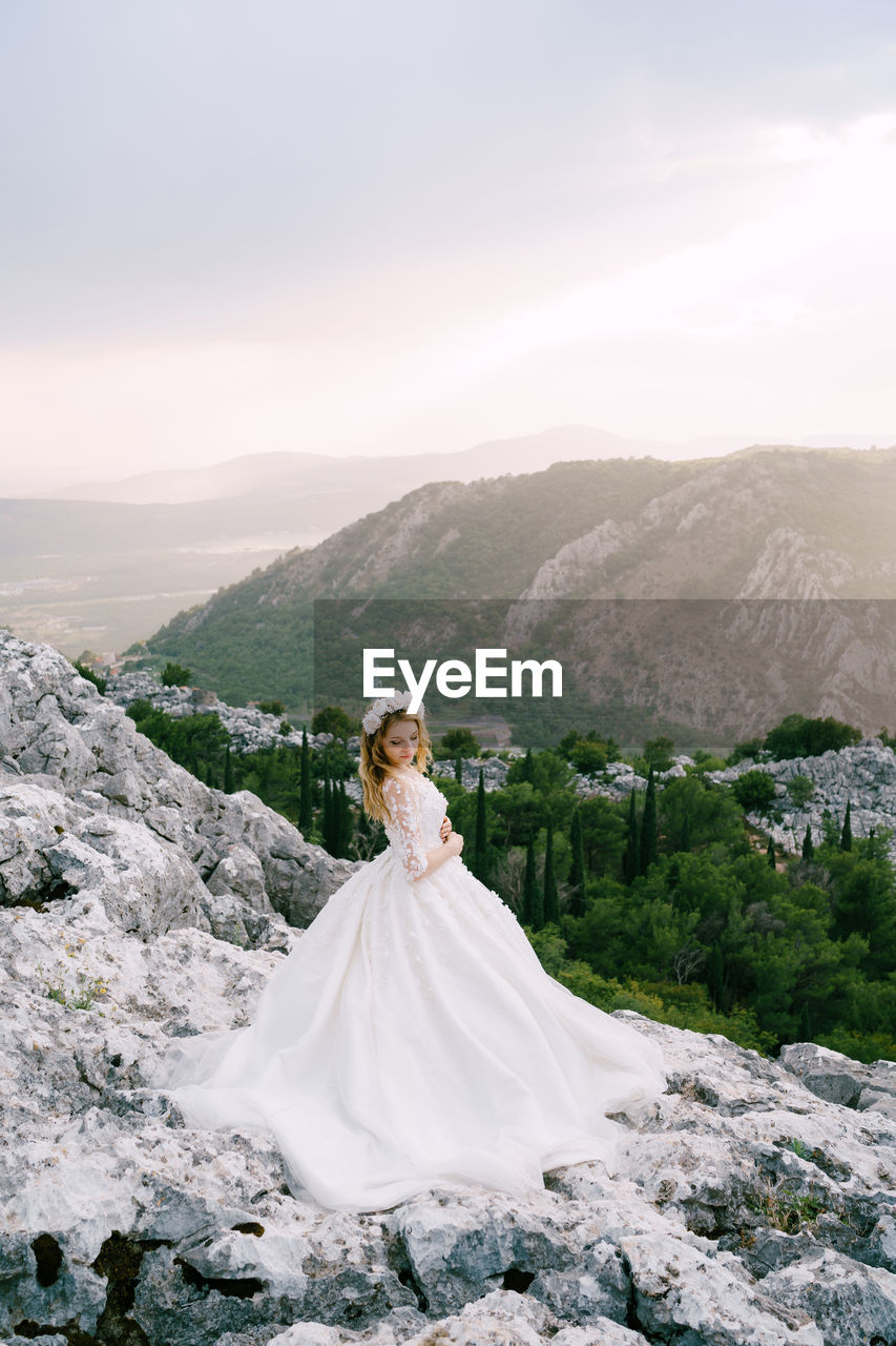 WOMAN STANDING AGAINST MOUNTAIN