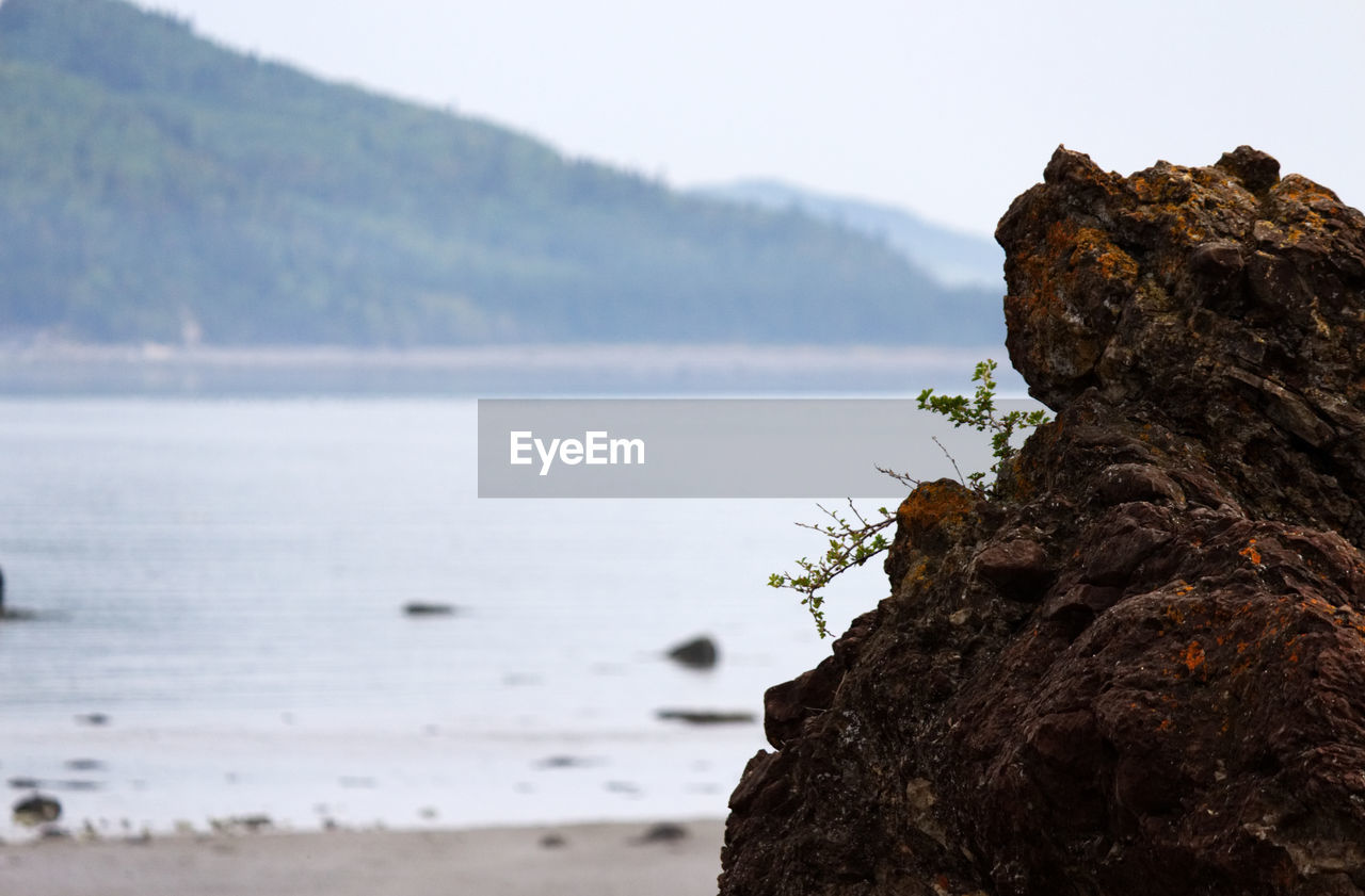 CLOSE-UP OF ROCKS ON SEA AGAINST SKY