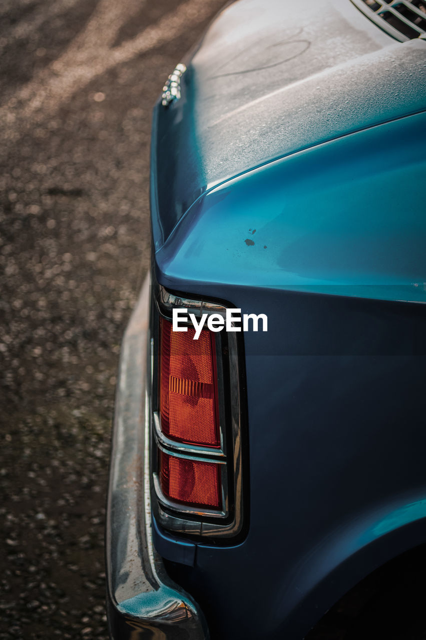 CLOSE-UP OF BLUE CAR ON ROAD