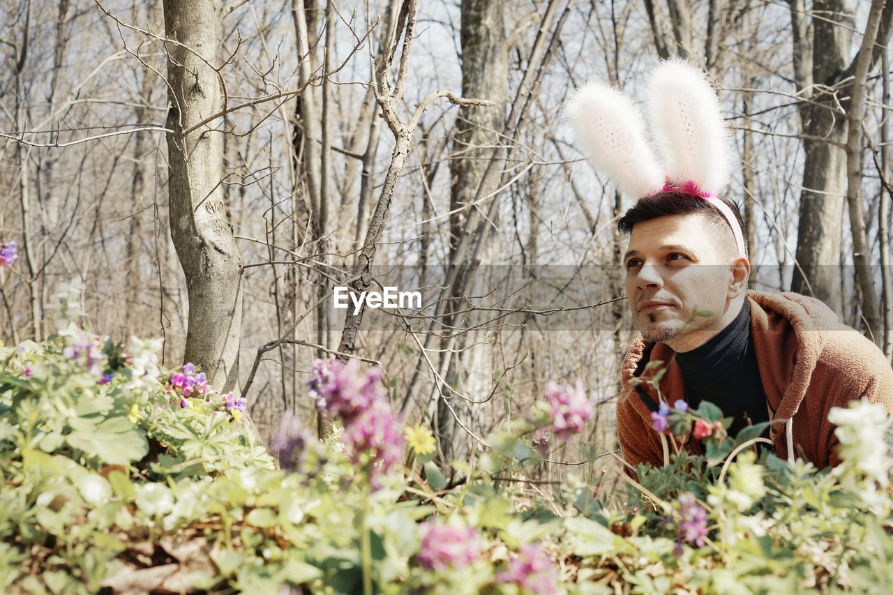 Young man wearing bunny ear headband in park