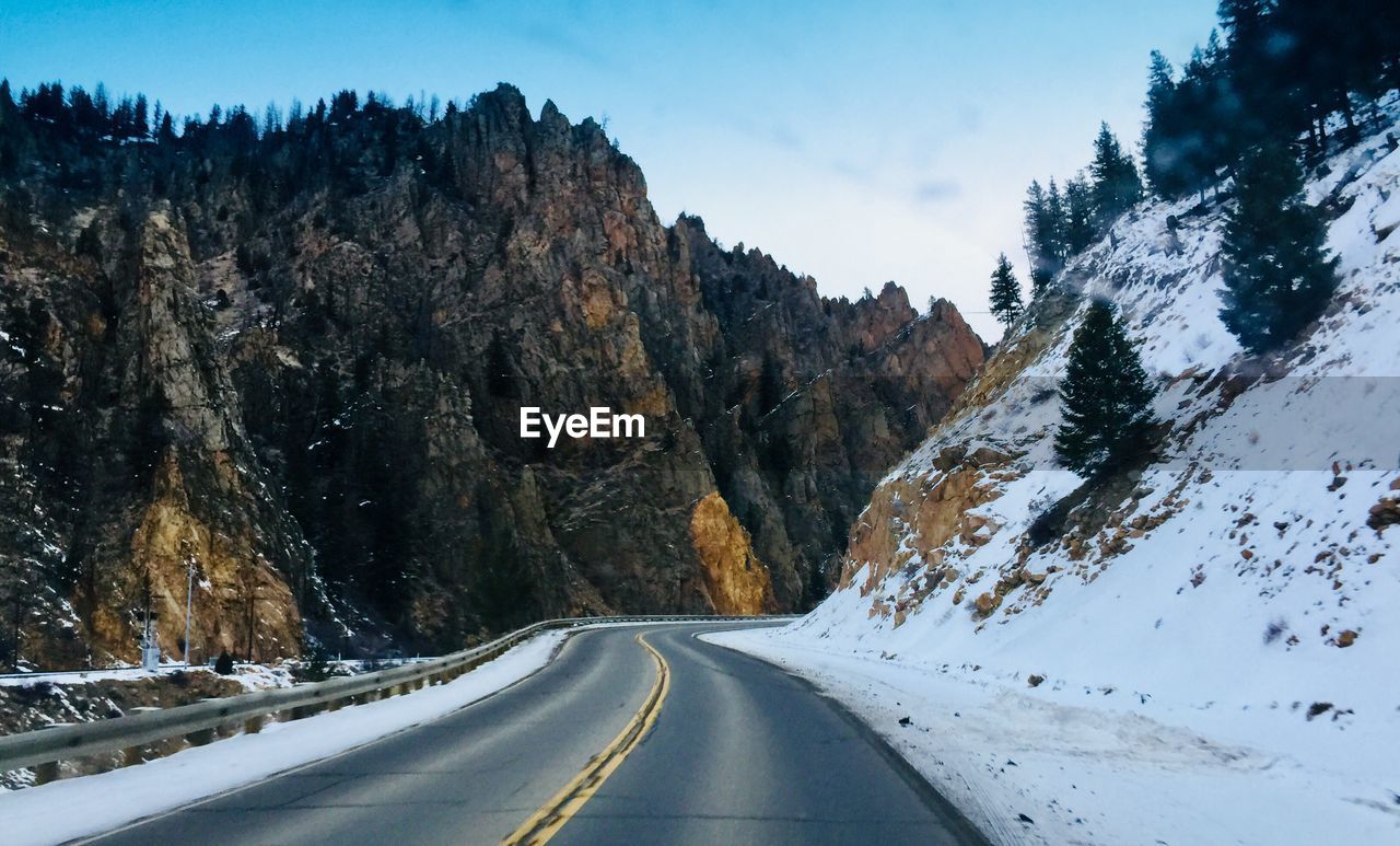 Road amidst snow covered mountains against sky