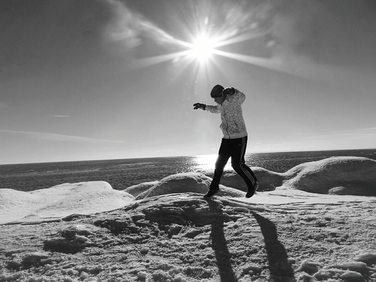 Side view of boy jumping on snowcapped field against lake michigan