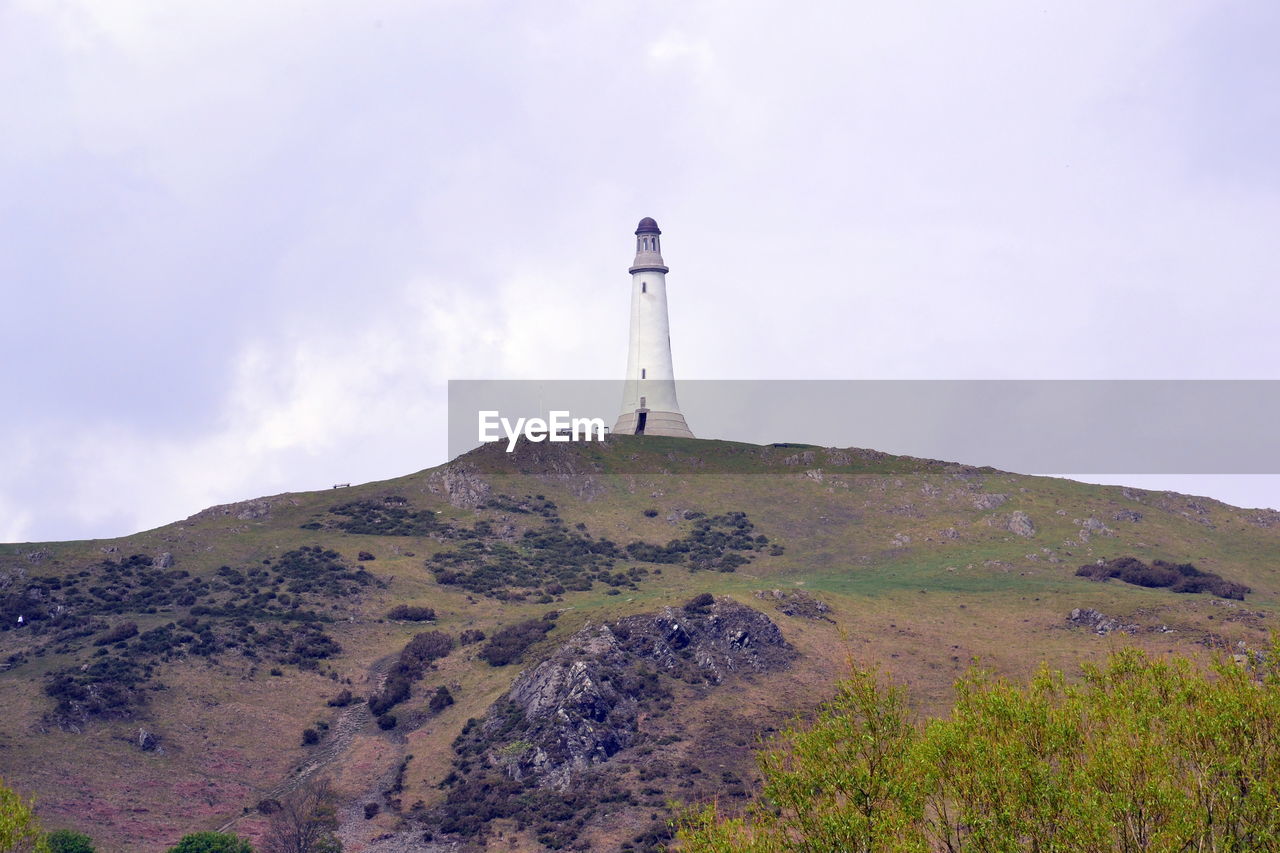 LOW ANGLE VIEW OF LIGHTHOUSE AMIDST BUILDING AGAINST SKY