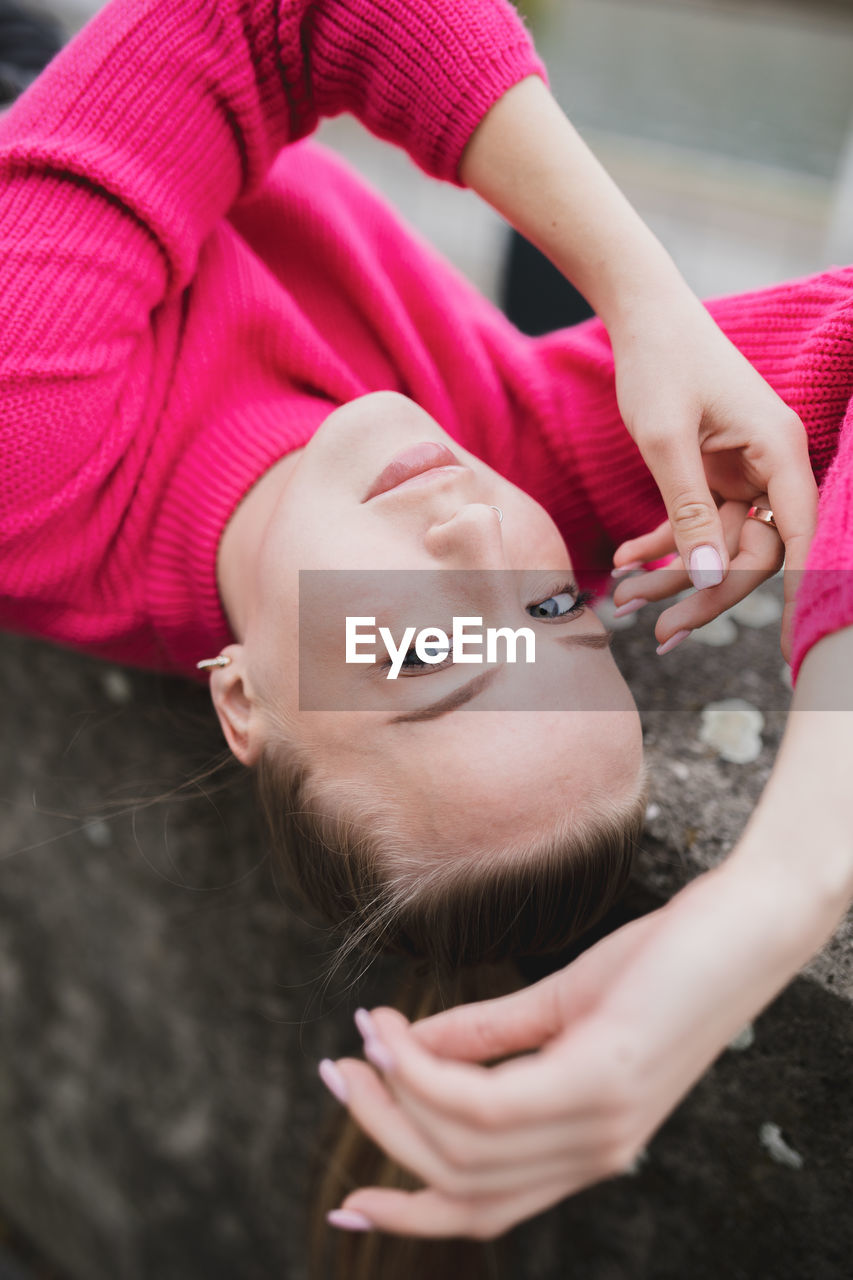 High angle portrait of young woman lying outdoors