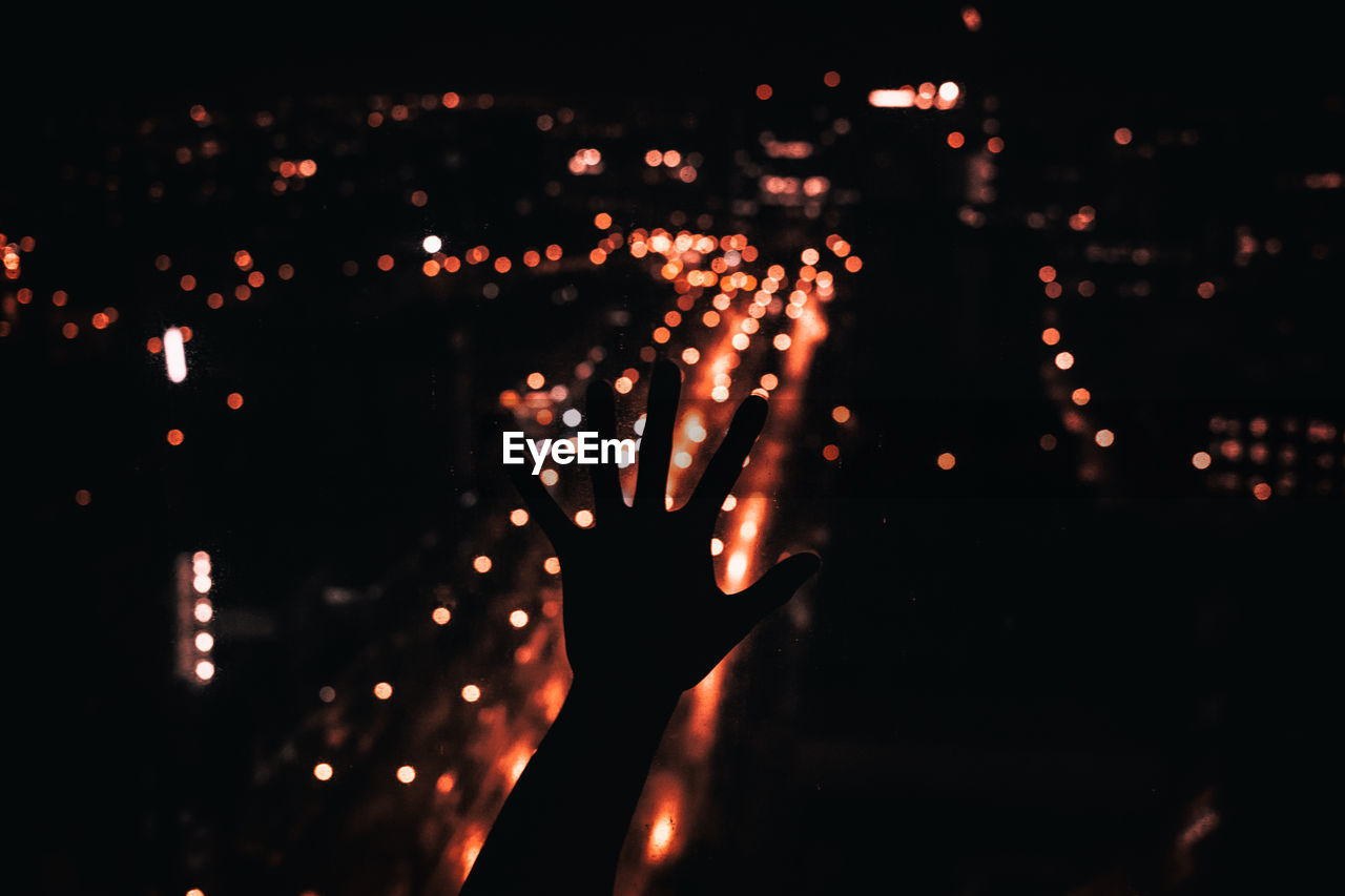 Close-up of hands against illuminated city lights