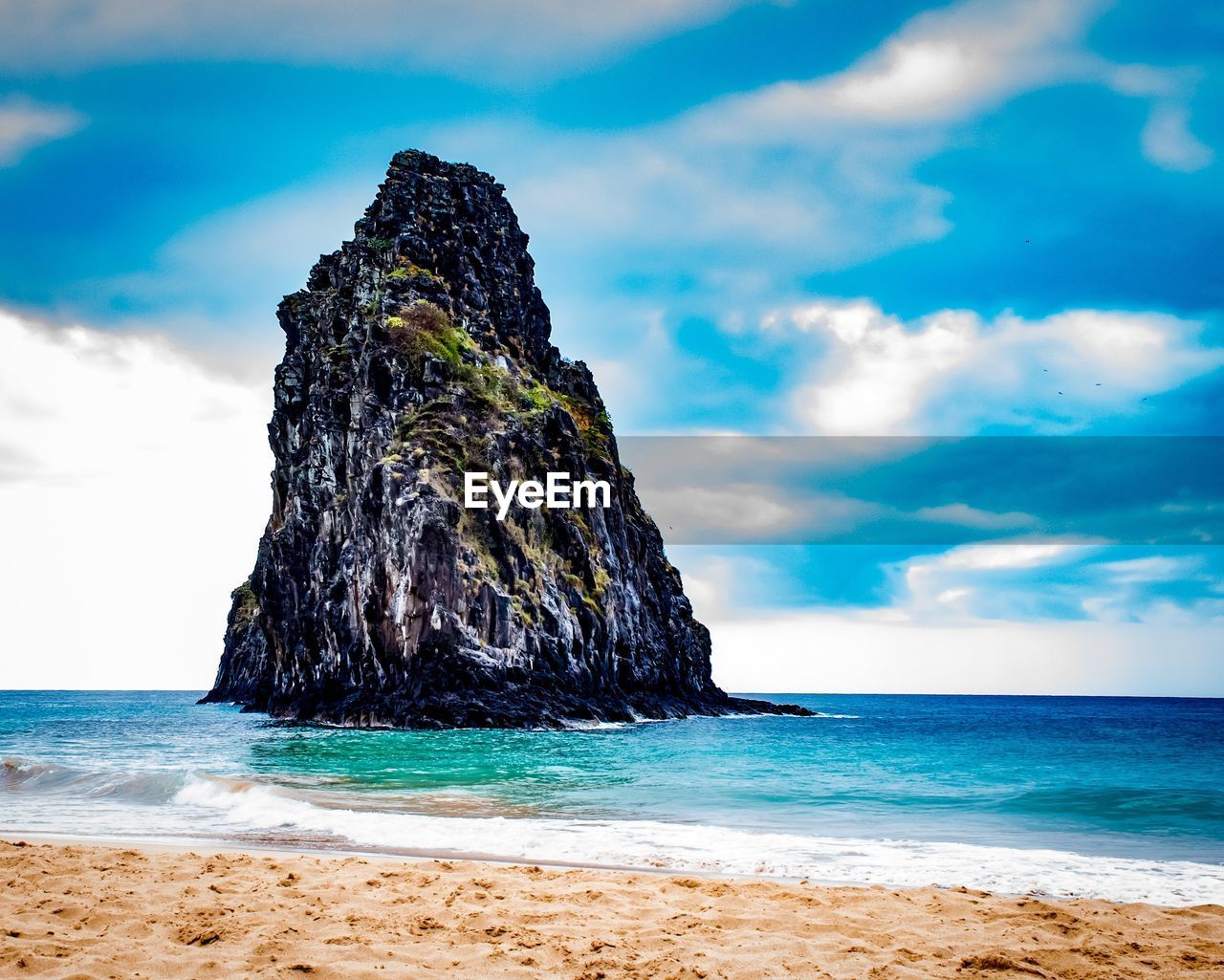 Rock formation on beach against sky
