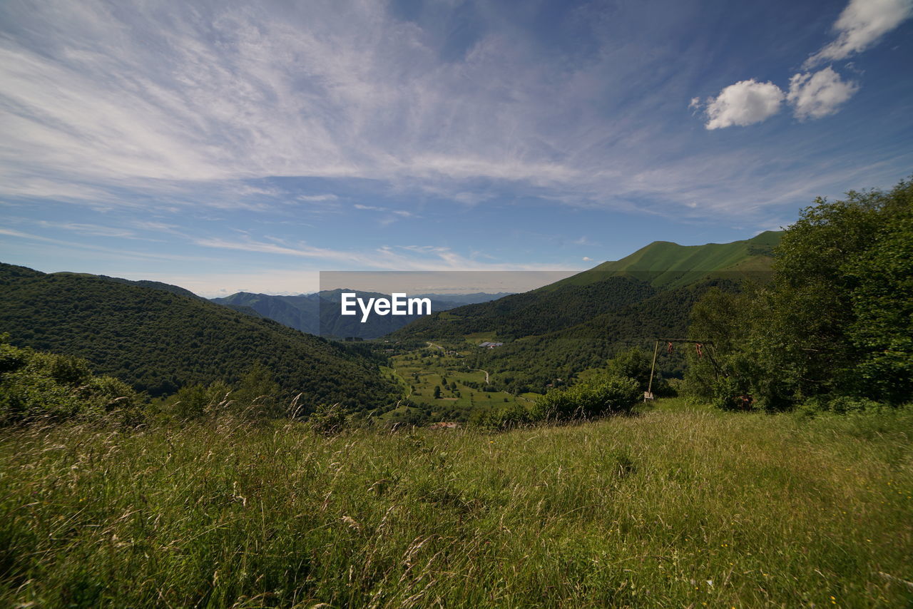 Scenic view of green landscape and mountains against sky