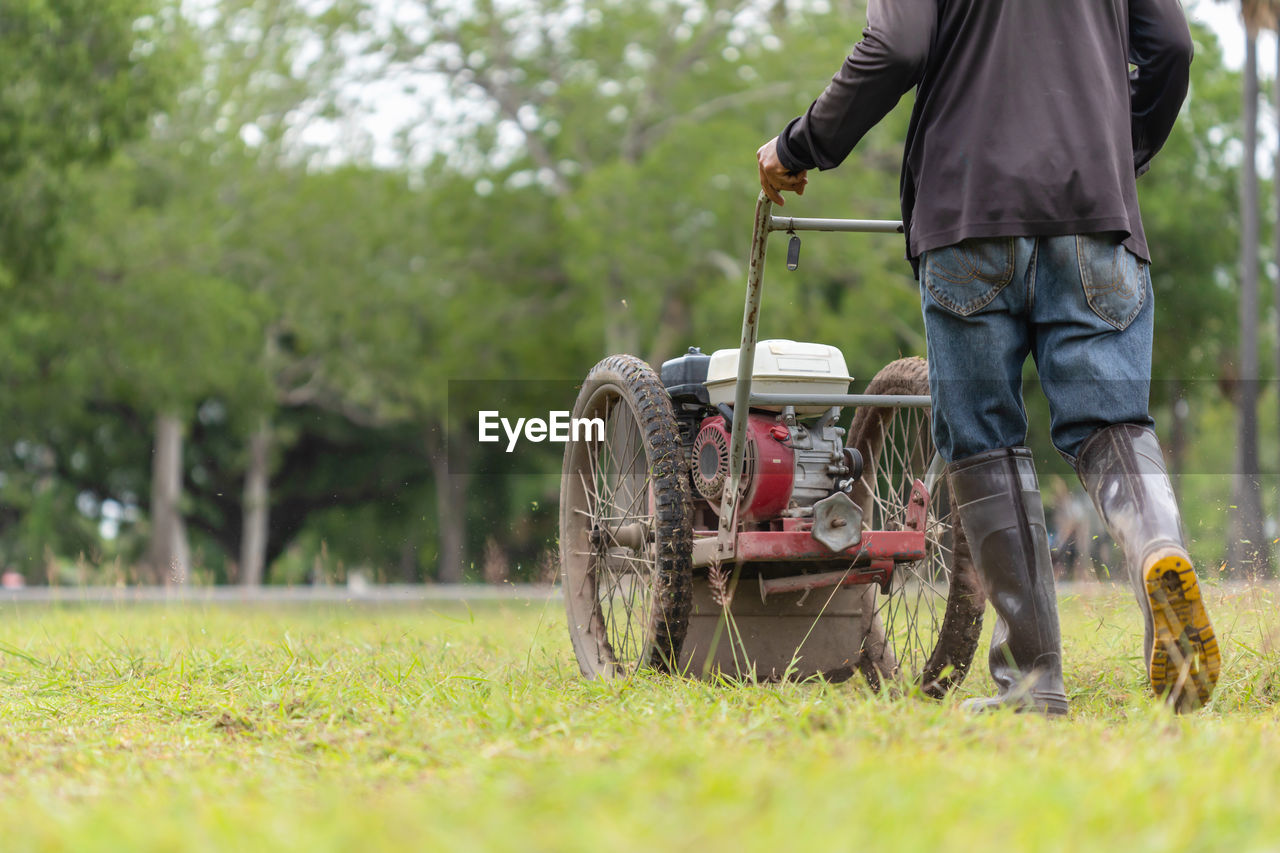 Thai worker mowing grass with machine in the public garden