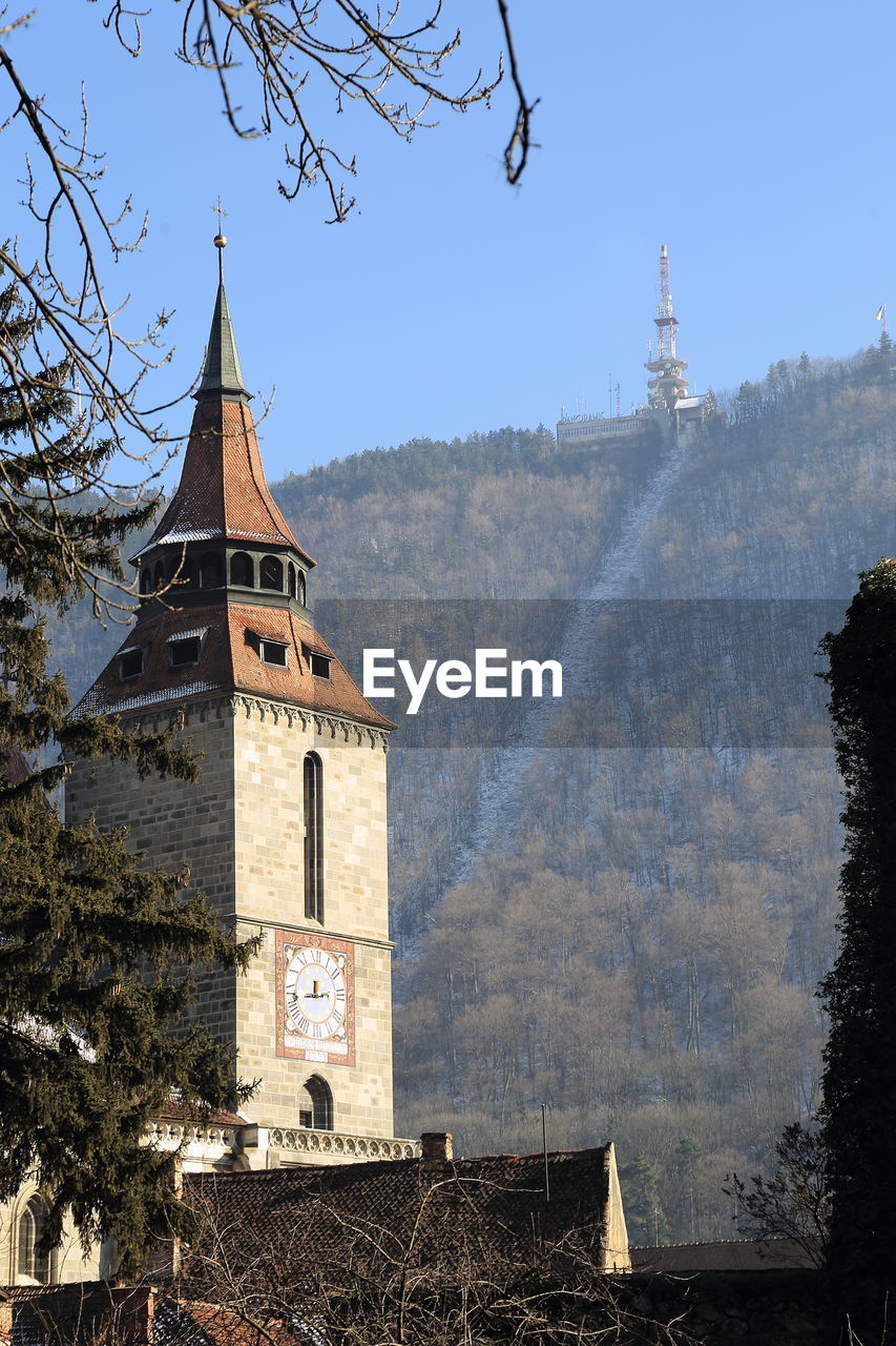 Low angle view of church by tree mountain against clear sky