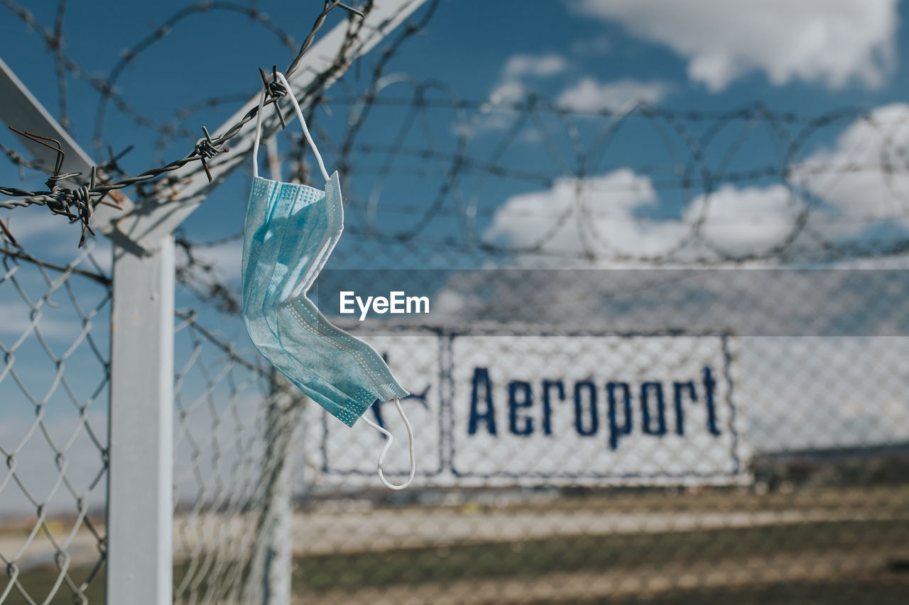 CLOSE-UP OF TEXT ON CHAINLINK FENCE AGAINST SKY