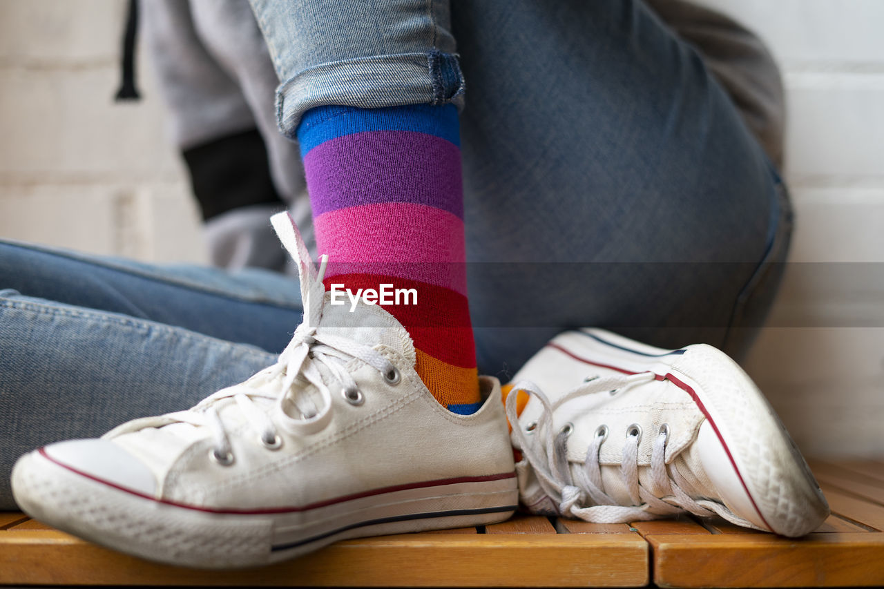 Woman sitting with her white sneakers and colored socks.