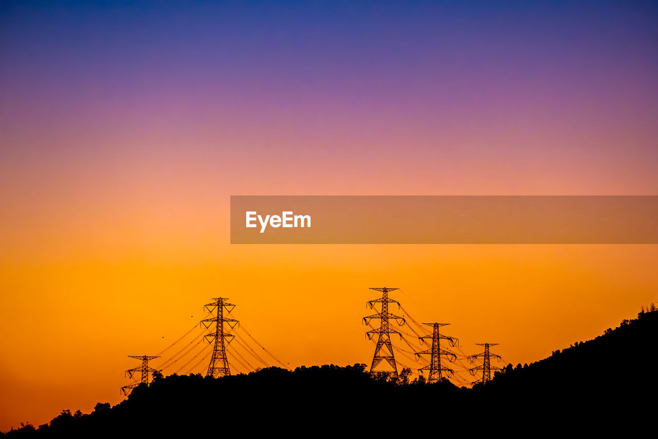 Low angle view of electricity pylon against sky during sunset