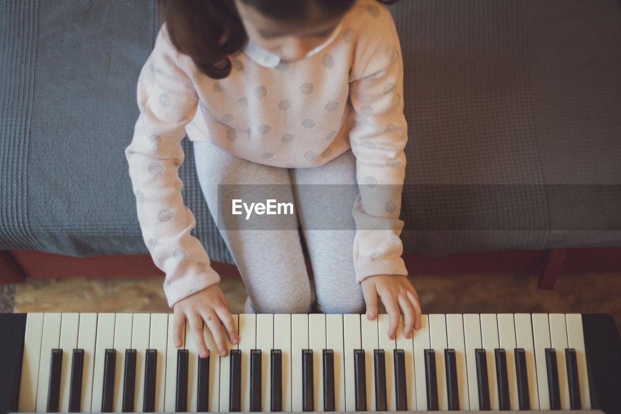 A little girl plays the electric piano.