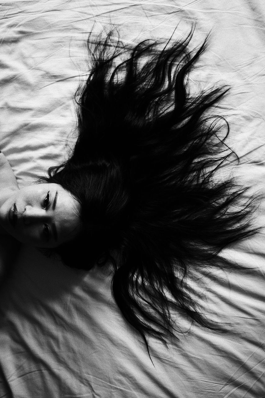 HIGH ANGLE VIEW OF WOMAN RESTING ON BED