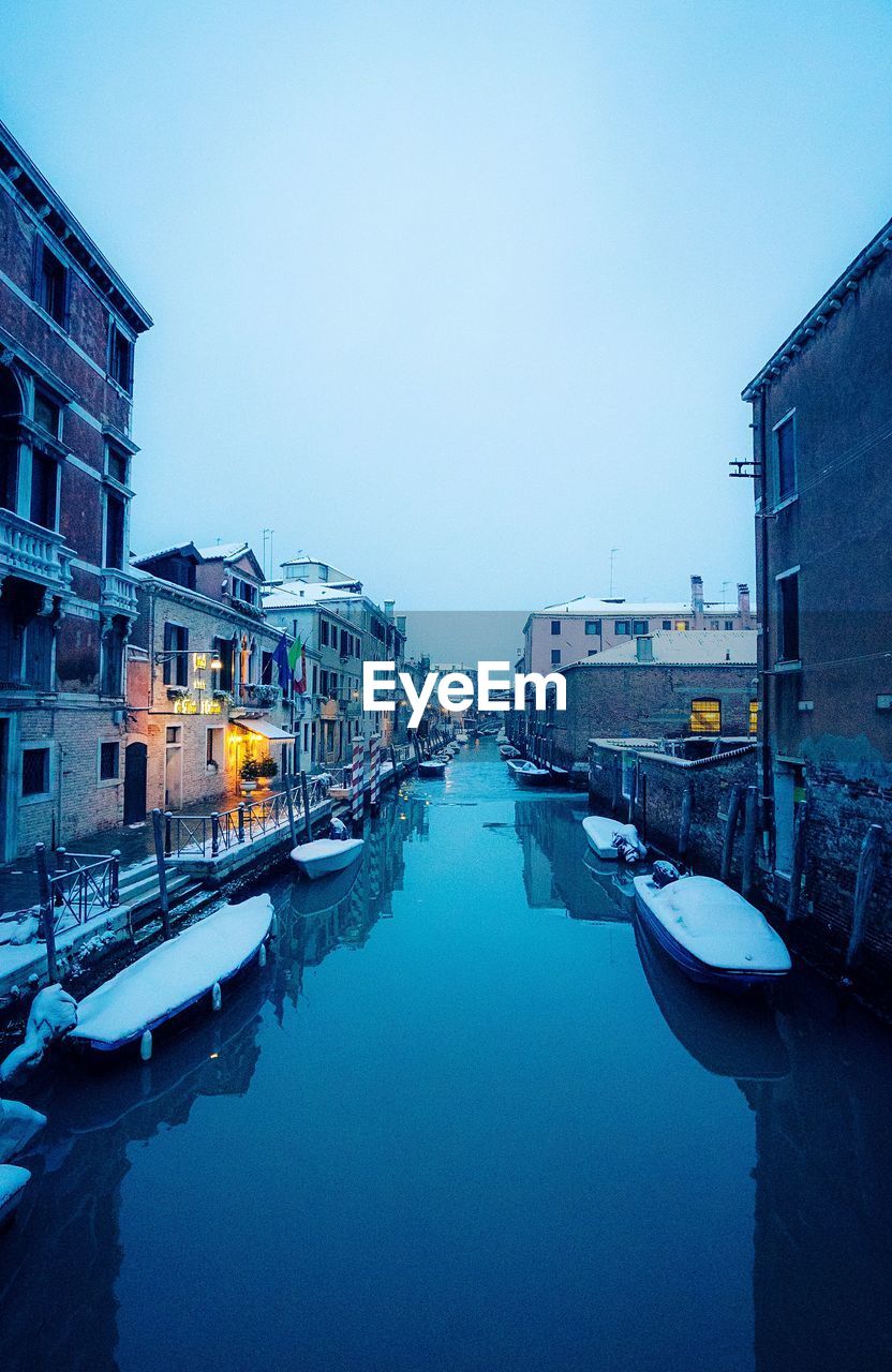 Canal amidst buildings in city against clear sky