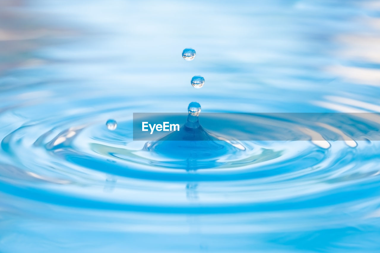 Close-up of drop falling on blue water