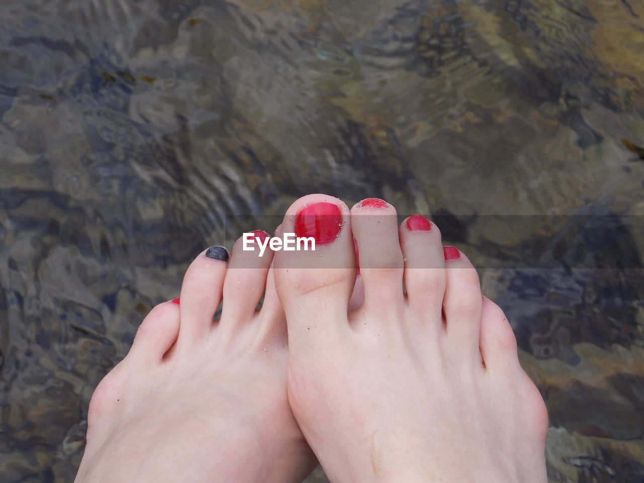 Low section of woman with painted toenails over lake