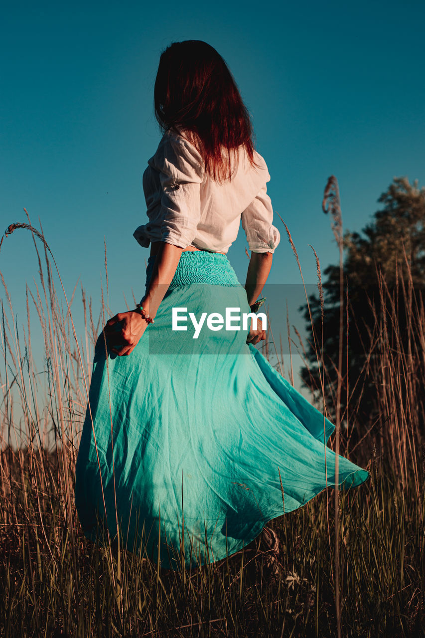 Rear view of woman on field against sky