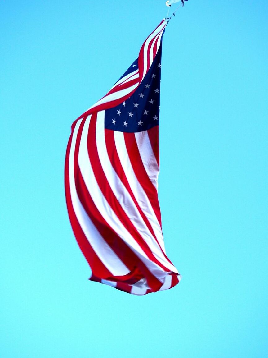 LOW ANGLE VIEW OF AMERICAN FLAG AGAINST CLEAR SKY