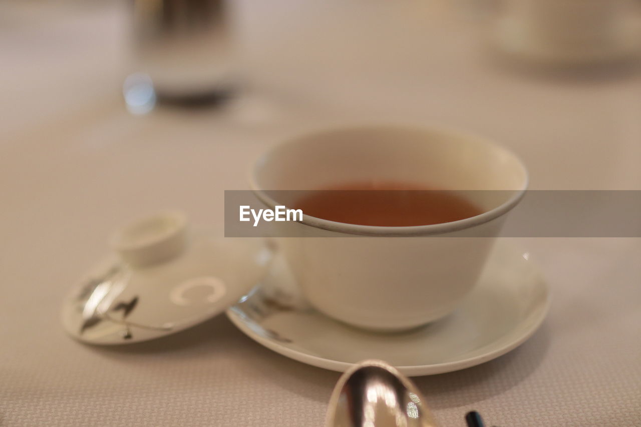 food and drink, cup, mug, drink, tea, refreshment, tea cup, hot drink, spoon, crockery, saucer, coffee cup, kitchen utensil, indoors, eating utensil, coffee, close-up, no people, table, focus on foreground, assam tea, da hong pao, food, porcelain, relaxation, selective focus, teaspoon, tableware, darjeeling tea, ceramic