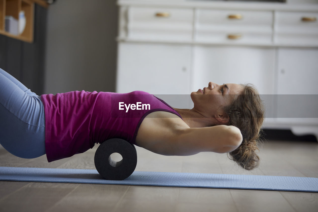 Woman using roller while doing exercise at home