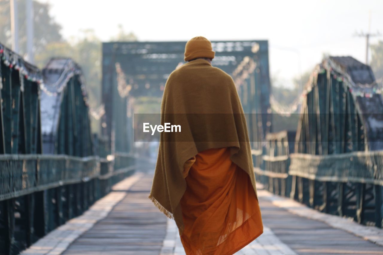 Rear view of monk walking on footbridge