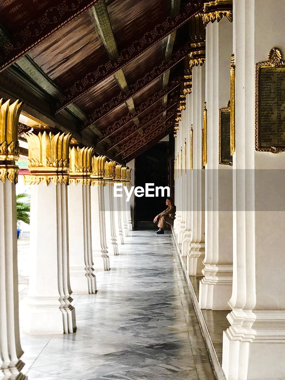 REAR VIEW OF MAN WALKING ON CORRIDOR OF BUILDING