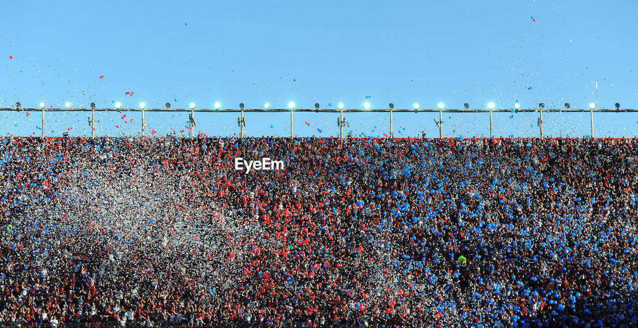 People in stadium against clear blue sky