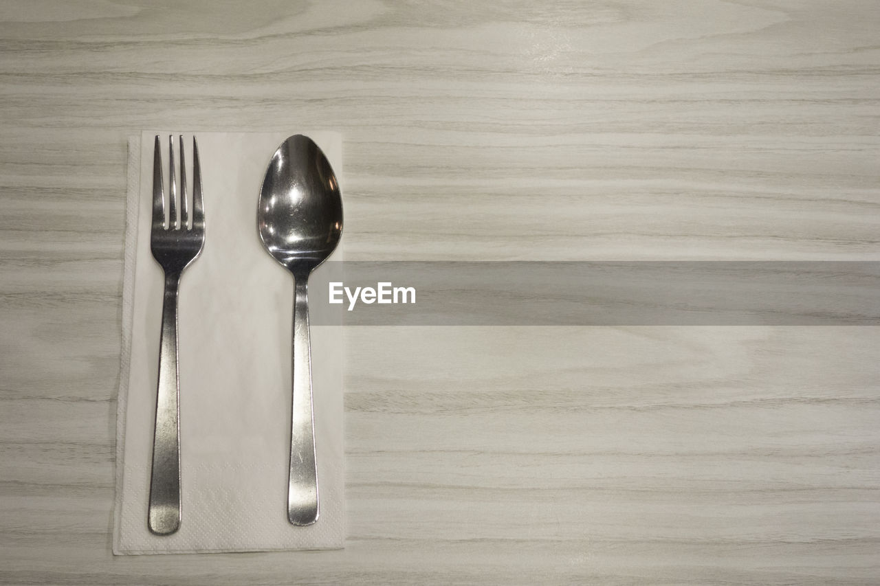 High angle view of spoon and fork on wooden table