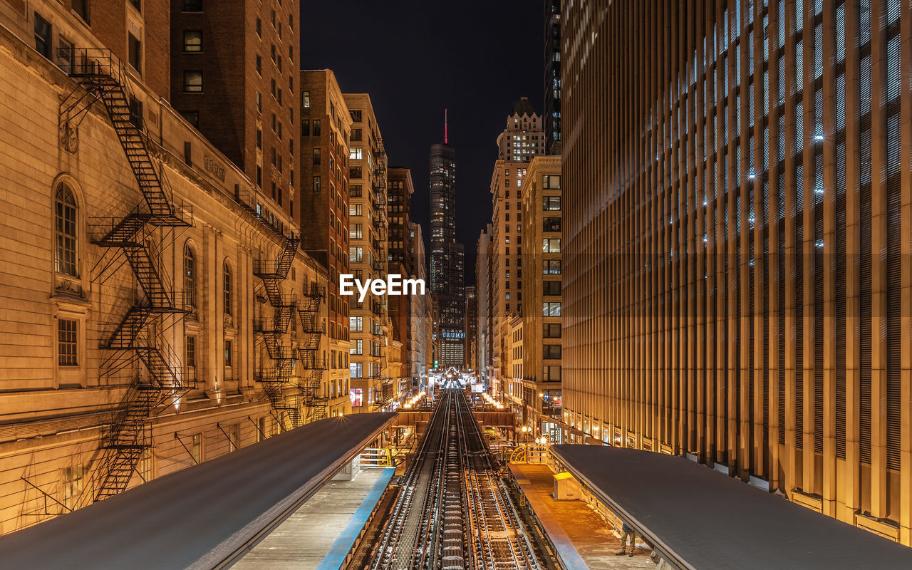 High angle view of railroad station platform amidst illuminated city at night