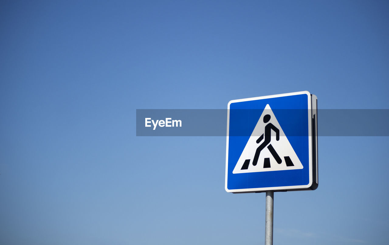 Road sign pedestrian crossing on a background of blue sky