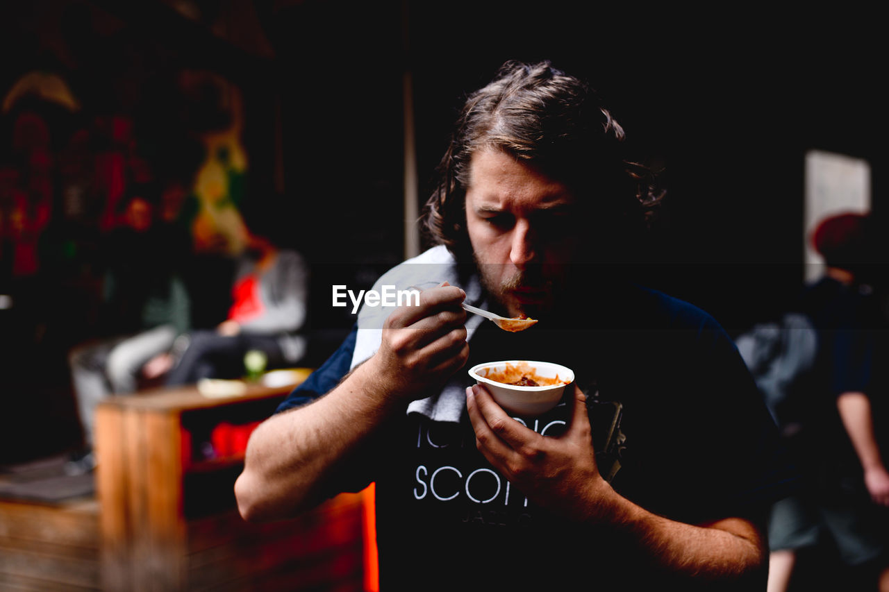 Man eating food while standing at market