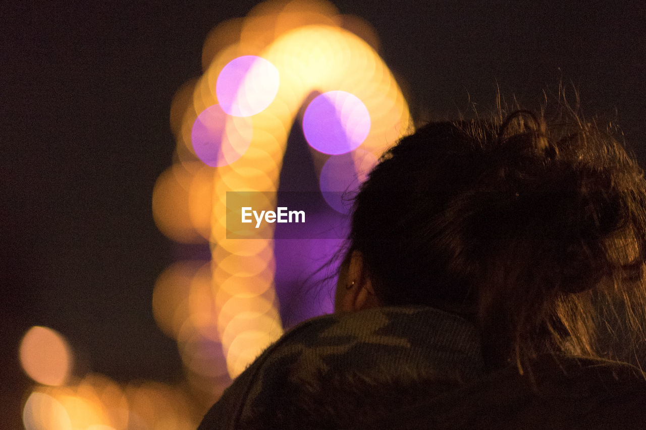 REAR VIEW PORTRAIT OF WOMAN WITH ILLUMINATED LIGHT PAINTING