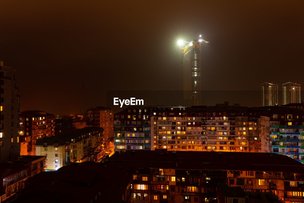 ILLUMINATED BUILDINGS AGAINST SKY IN CITY AT NIGHT