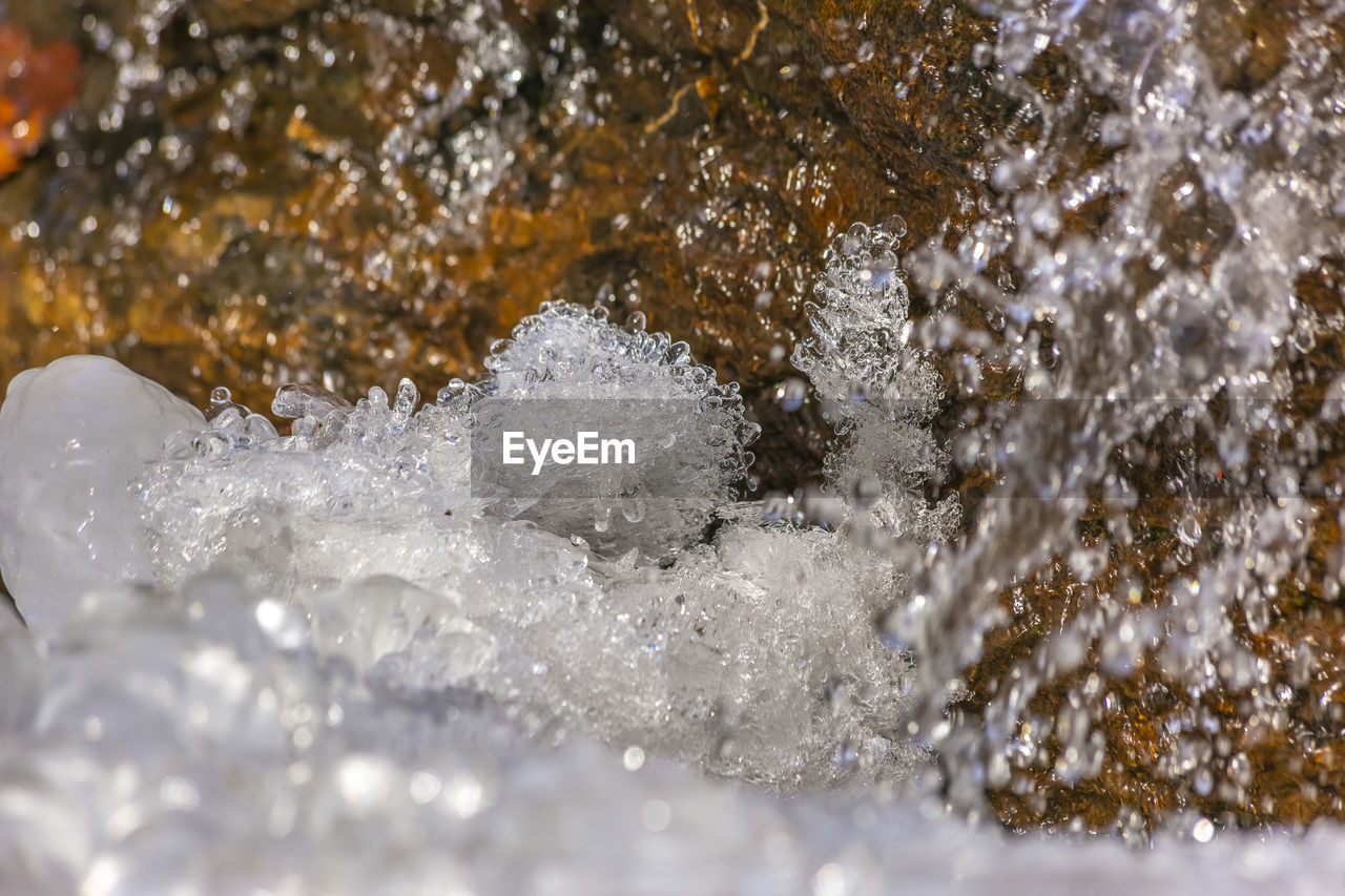 CLOSE-UP OF WATER FLOWING THROUGH ROCKS