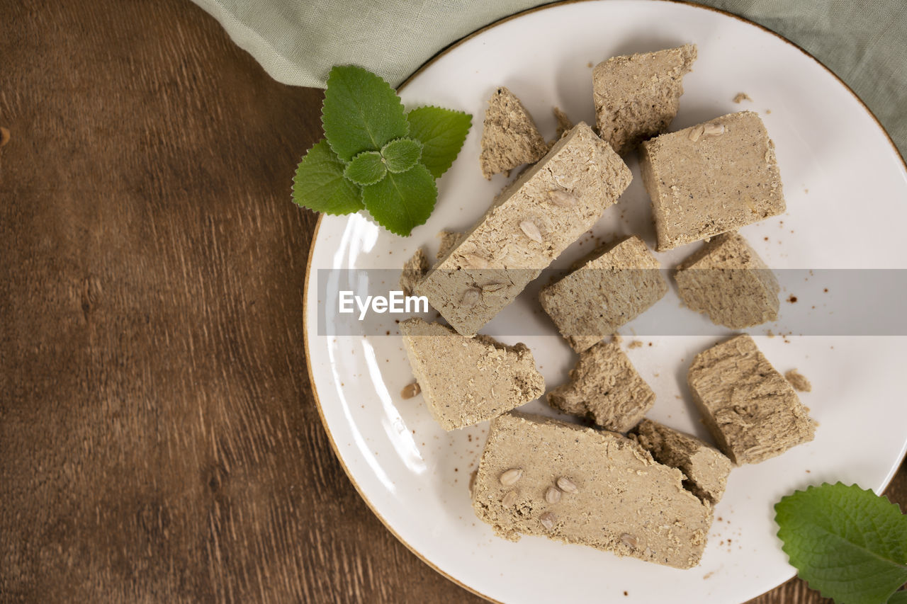 Traditional eastern sweets halva with sunflower seeds and mint leaves on a white plate. top view.