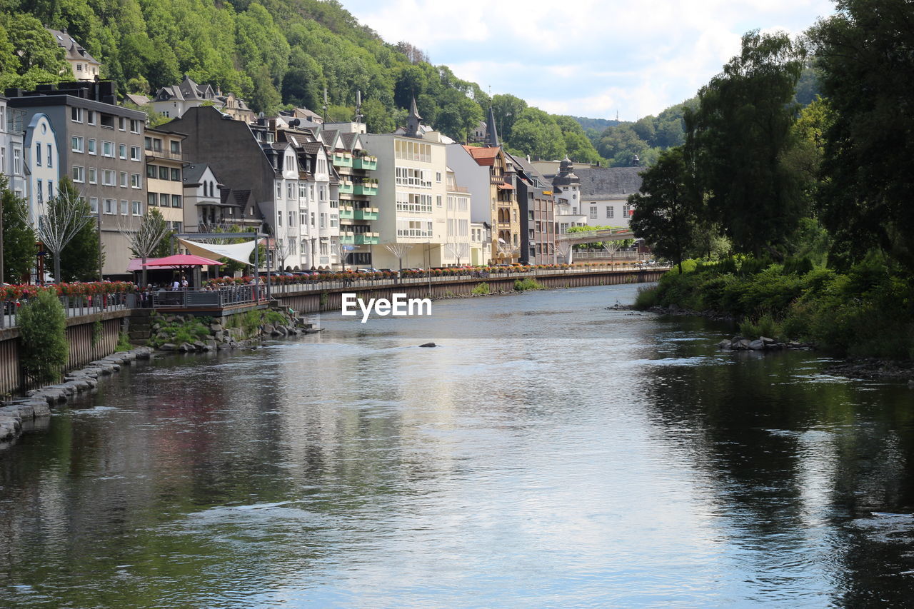 River by houses and buildings against sky