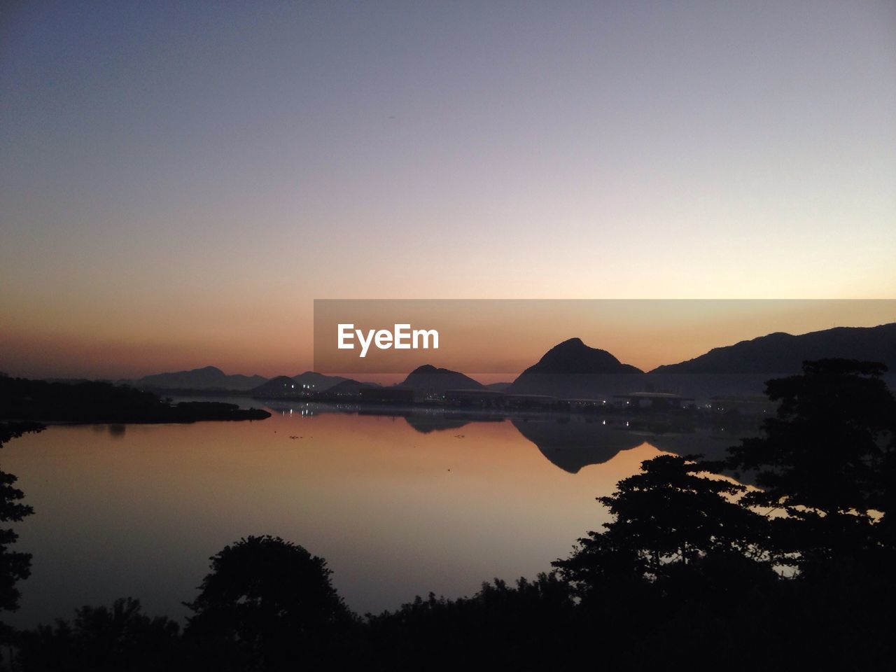 SCENIC VIEW OF LAKE BY SILHOUETTE MOUNTAINS AGAINST SKY