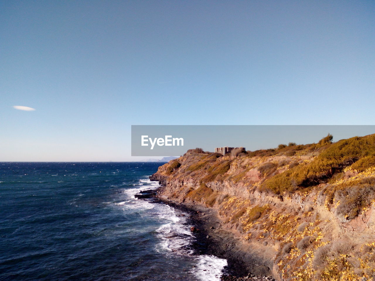 SCENIC VIEW OF SEA BY CLIFF AGAINST CLEAR BLUE SKY