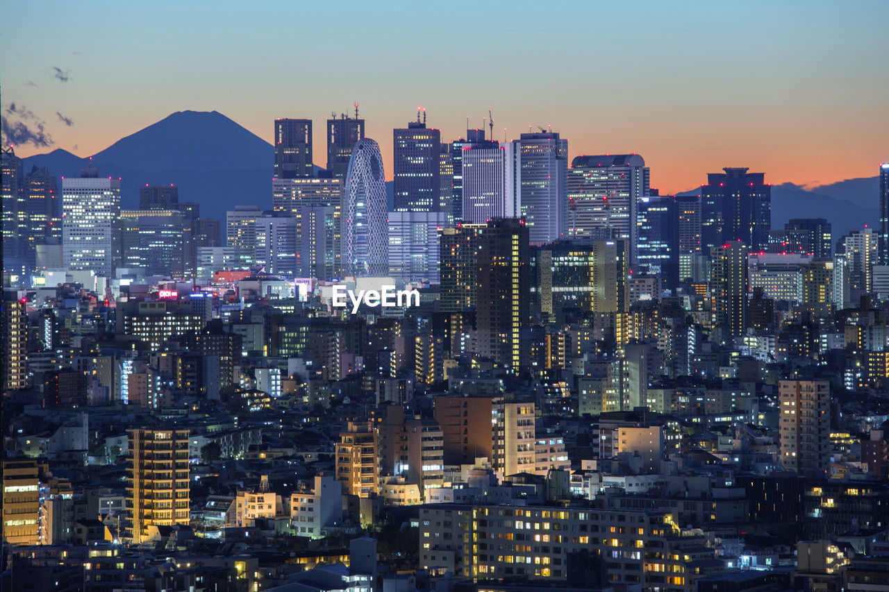 Illuminated cityscape against sky during sunset